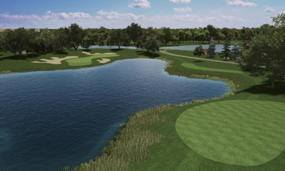 Golf course with a large body of water and green grass under a clear sky.
