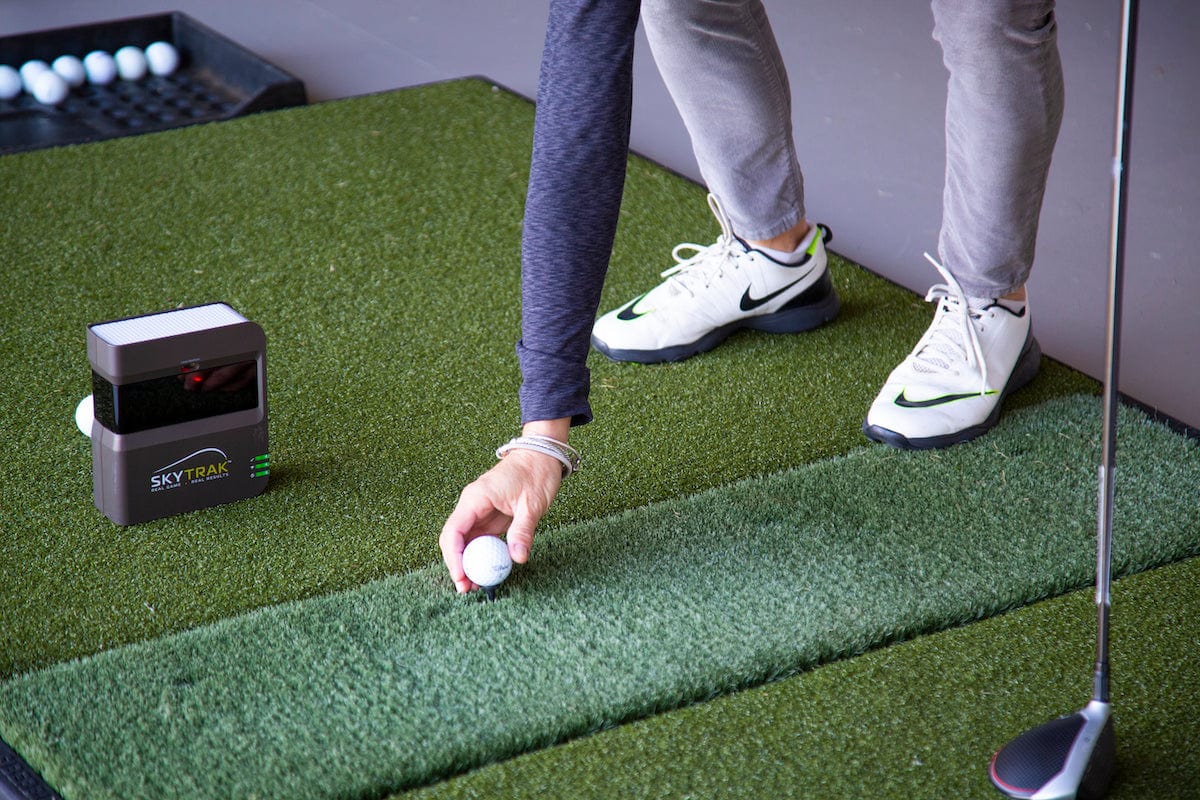 Golfer setting up a ball on a golf mat with the SKYTRAK Launch Monitor tracking performance