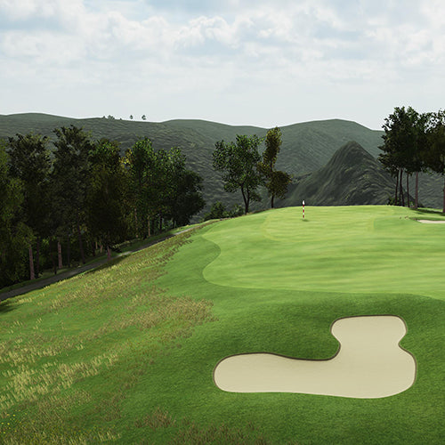 Golf course with a green and sand bunker, surrounded by trees and mountains.
