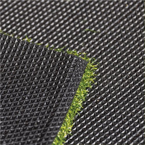 Close-up of textured black rubber mat with green grass peeking through